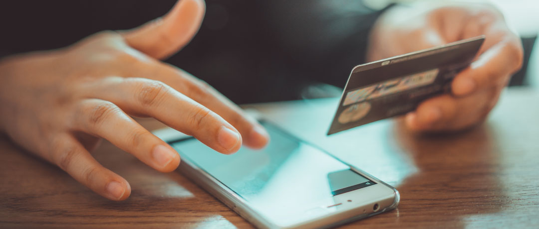 person using cellphone holding credit card