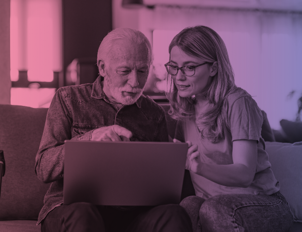 woman helping senior citizen at laptop