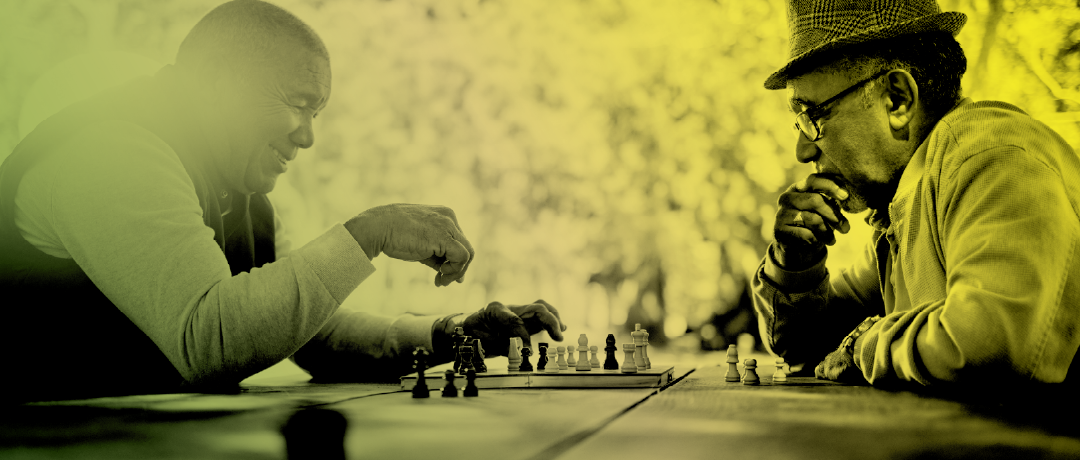 two men playing chess in the park