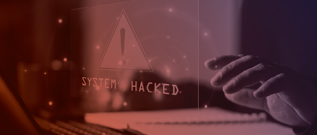 person at laptop with sign that says system hacked