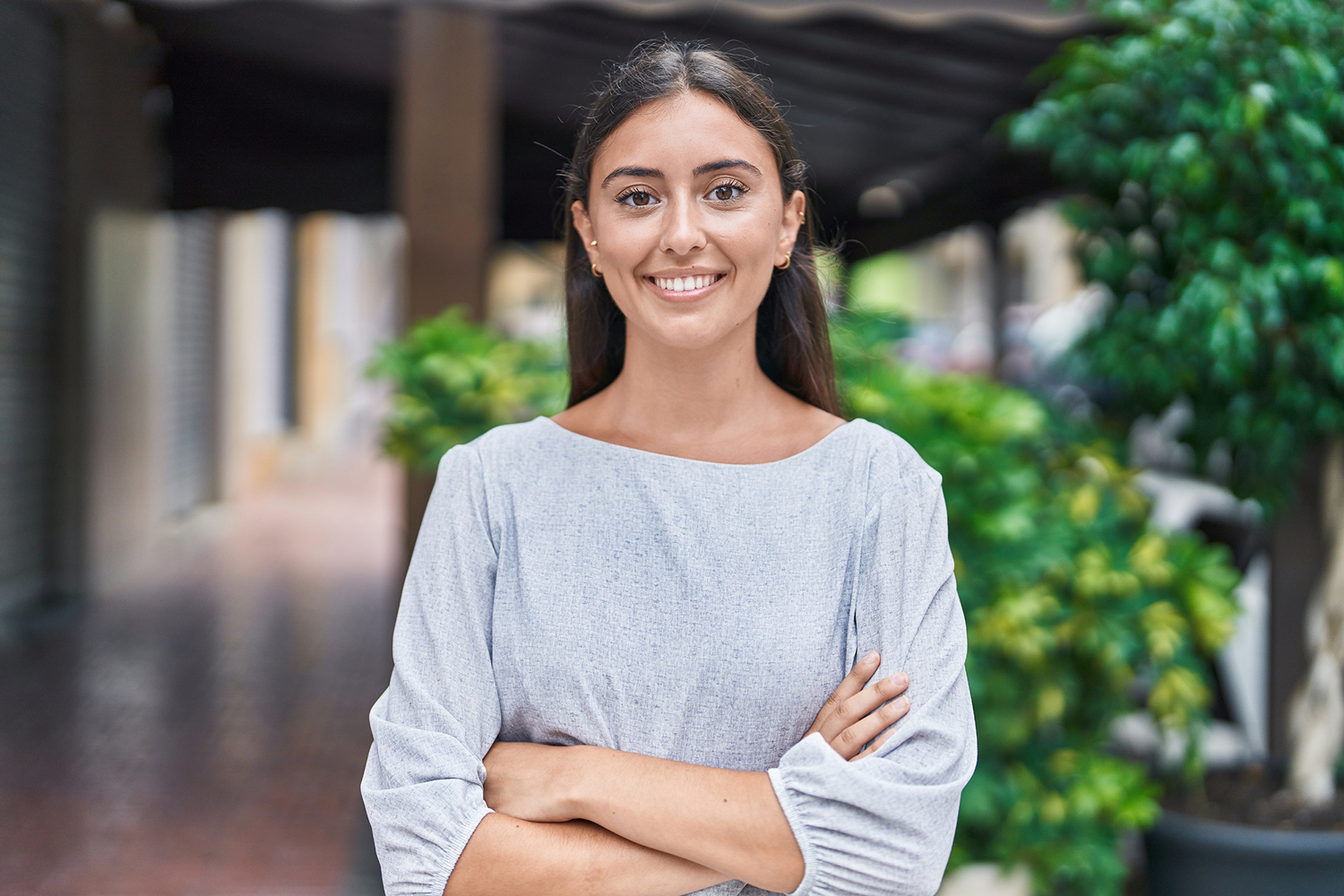 Young beautiful hispanic woman standing with arms crossed gesture at street